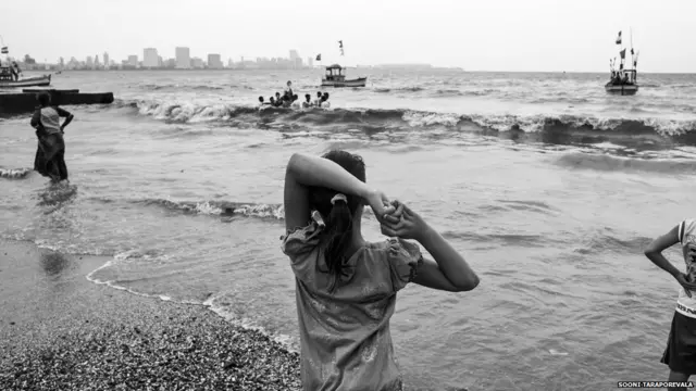 A girl looks at the ocean while standing on a beach in Mumbai