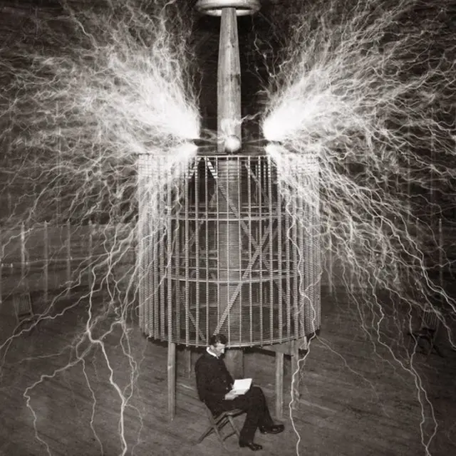 1899年，特斯拉在科罗拉多泉的实验室，背后是他发明的"放大发射器"（magnifying transmitter）