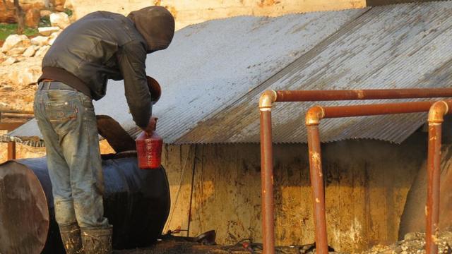 Сириец наливает сырую нефть в ведро в Идлибе