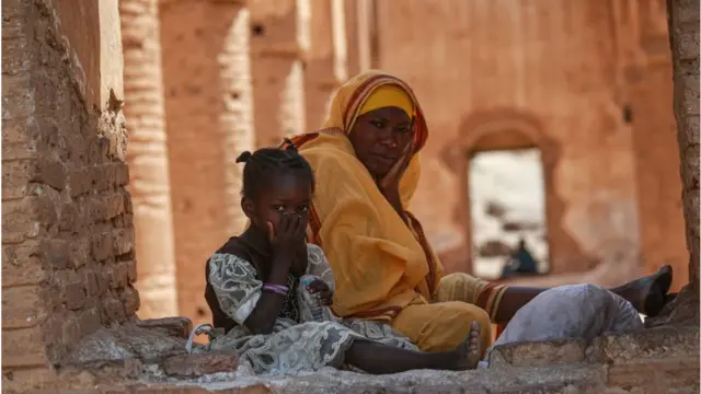 A woman and a child sitting on the floor at the shrine of Abu Jalabiya.