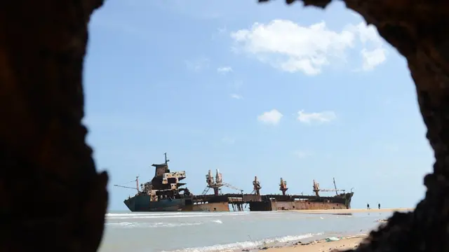 The wreckage of the Jordanian ship Farah-3, which ran aground after being captured by Tamil Tiger rebels in December 2006, is seen in the background as unseen Sri Lankan troops uncover a cache of weapons exposed by recent storm surges and heavy rains near the north-eastern town of Vellamullivaikkal in the Mullaittivu district on November 2, 2012. A storm surge in Sri Lanka's northeast has exposed buried artillery guns of Tamil Tiger rebels in a region where the final battles of the country's 37-year conflict were fought, the army said. Troops stumbled on four 152mm artillery barrels and one 130 mm piece believed to have been used by Tiger guerrillas during their last stand in the district of Mullaittivu, army spokesman Ruwan Wanigasooriya said. AFP PHOTO/ Ishara S. KODIKARA (Photo credit should read Ishara S.KODIKARA/AFP/Getty Images)