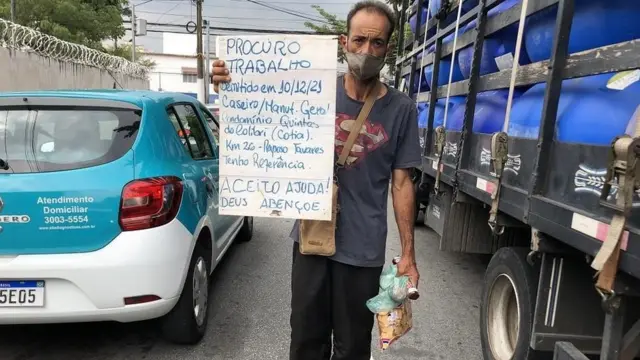 José Gonçalves Neto segurando placa pedindo ajuda entre carros