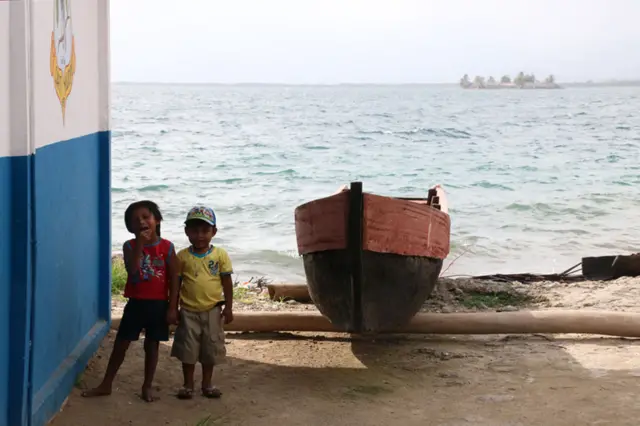 Crianças gunas junto a uma canoa