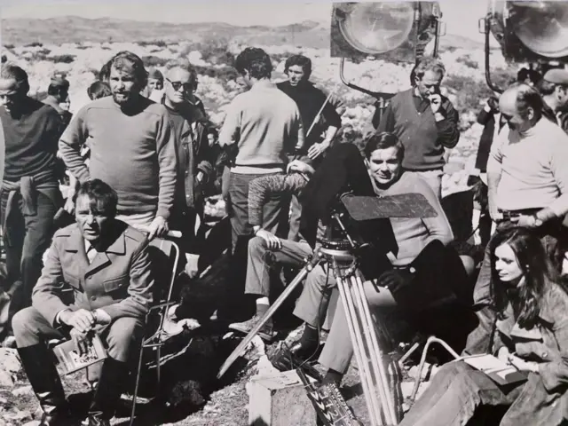 Barton u pauzi snimanja čita knjigu Dnevnik revolucionara, Popović za kamerom, a u uglu Manca Kosir glumica i novinarka iz Ljubljane