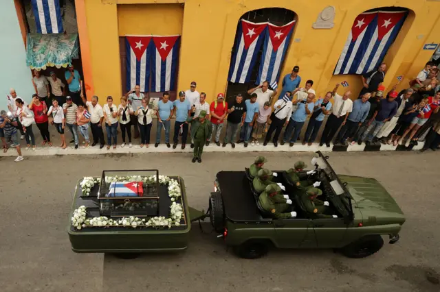 People line the street to make photographs and wave flags in Santa Clara, Cuba, as the remains of former Cuban President Fidel Castro pass by on a cross-country journey from Havana to Santiago de Cuba on 1 December 2016.