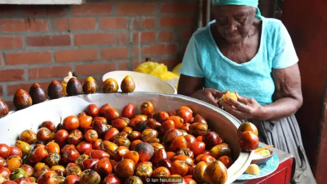 Seorang perempuan tua mengupas buah tropis di Cali.