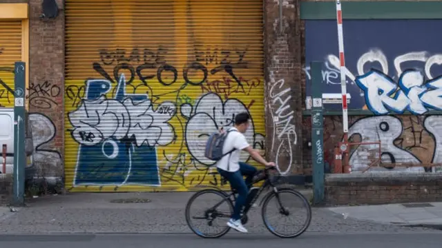 Cycliste devant des commerces fermés.