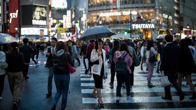 commuters make their way over the Shibuya crossing in central Tokyo