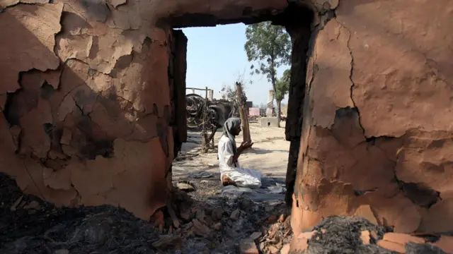 गोलाबारी से क्षतिग्रस्त मकान के बाहर नमाज पढ़ता एक मुसलमान