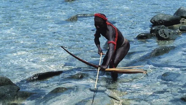 Um jarawa pescando com arco e flecha