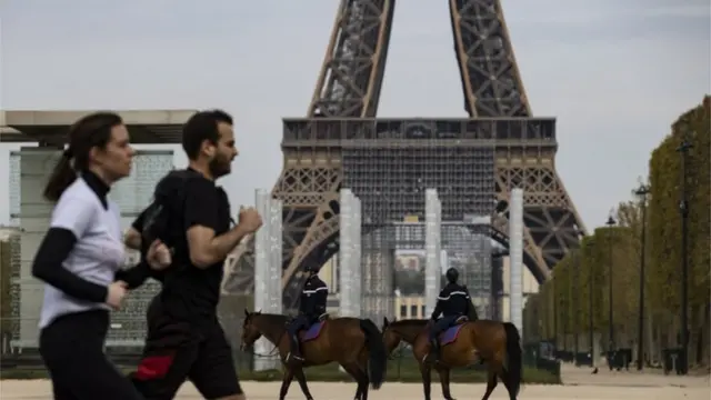 Homem e mulher correndo em frente à Torre Eiffel