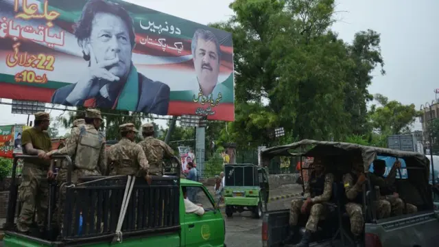 ইমরান খানের দলের নির্বাচনী ব্যানার। রাস্তায় টহল দিচ্ছে পাকিস্তানি সেনা