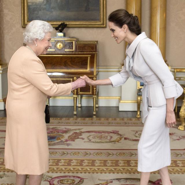 A atriz Angelina Jolie sendo condecorada com a insígnia de Dama Honorária da Ordem de São Miguel e São Jorge pela rainha Elizabeth 2ª no Palácio de Buckingham