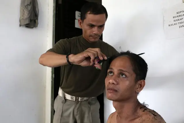 Polisi sipil sekaligus Wilayatul Hisbah Banda Aceh tengah memangkas rambut seorang transgender