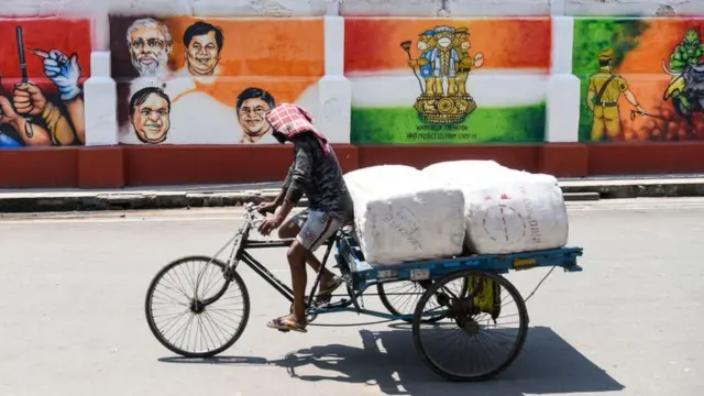 કોરોનાના સંદેશ લખેલી દીવાલ પાસેથી પસાર થઈ રહેલો શ્રમિક