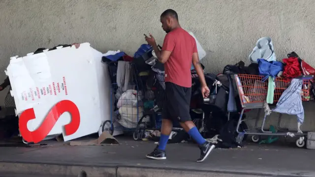 Peatón camina al lado de un habitáculo al aire libre en Los Ángeles