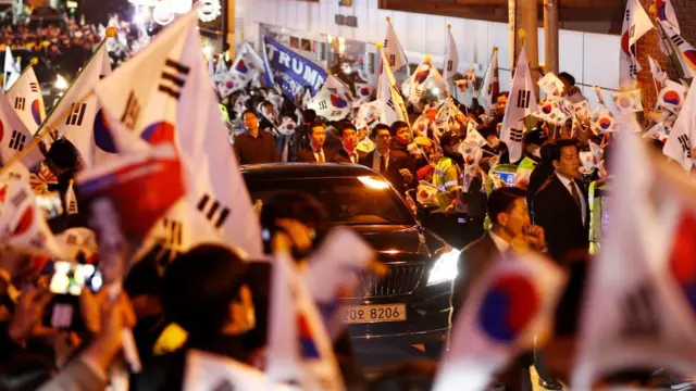 ประชาชนหลายร้อยคนรอต้อนรับ พวกเขาต่างโบกธงและร้องตะโกนให้กำลังใจ น.ส.ปัก