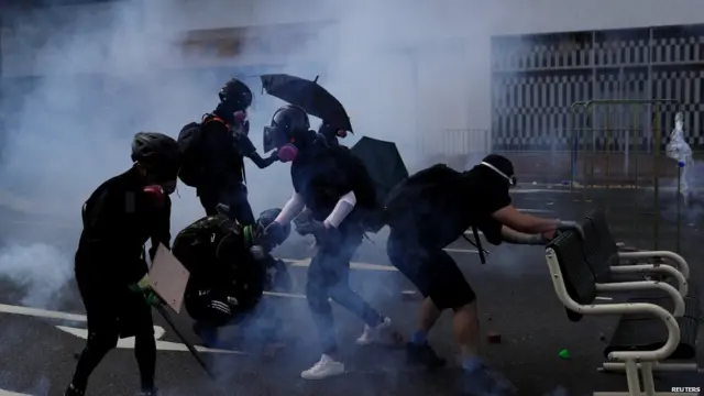 Anti-government protesters walk in tear gas during a protest in Sha Tin district, on China's National Day