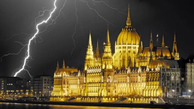 Hungarian Parliament Building lit at night, with lightning strikes across the sky above