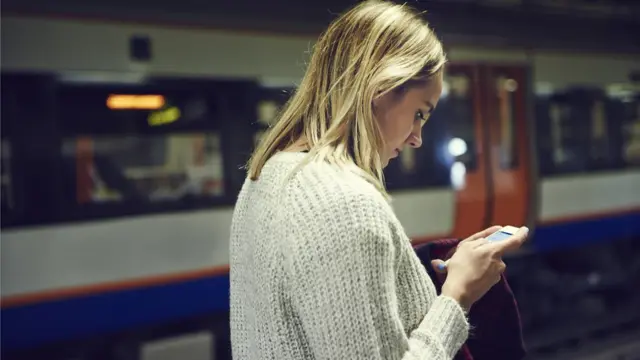 영국 지하철역에서 한 여성이 스마트폰을 들여다보고 있다.