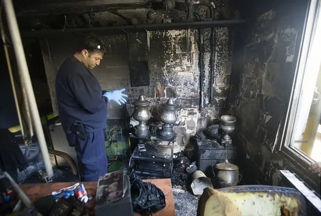 A policeman examines the scene after a fire at Beitar in February 2013. Police said arsonists torched the club offices over the signing of two Muslim footballers from Chechnya