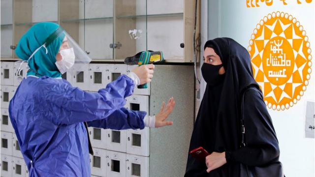 德黑兰大学校园清真寺入口处一名工作人员给一名进寺女生量体温（30/7/2020）