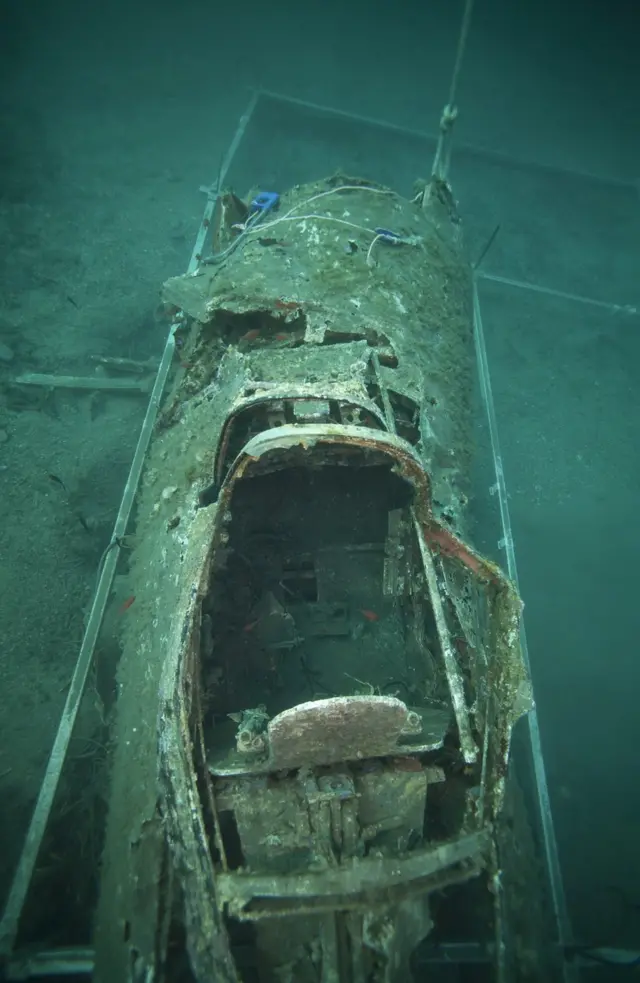 A French military diver member of the FS Pluton M622 navy de-mining ship, swims above the wreck of an USAAF P-47 Thunderbolt (Warthog) US fighter plane