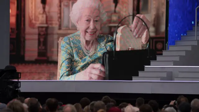 A screenshot of the Queen pulling a sandwich out of her bag