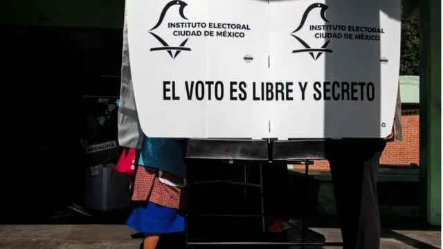 Persona en la urna de votación.