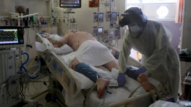 美国加州丘拉維斯塔一家医院内一名医护人员身穿全副保护服照顾新冠肺炎病人（12/5/2020）