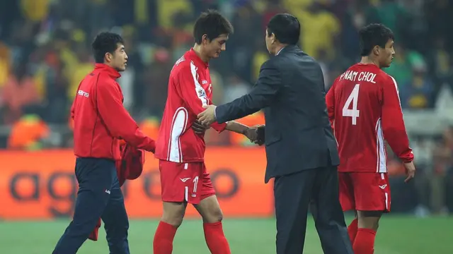 O treinador Kim Jong-Hun cumprimenta jogadores após derrota na Copa do Mundo