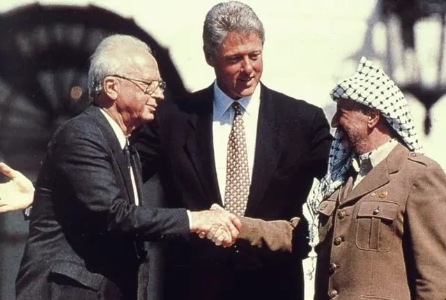 Yitzhak Rabin (on the left) and Yasser Arafat shake hands, as US President Bill Clinton looks on