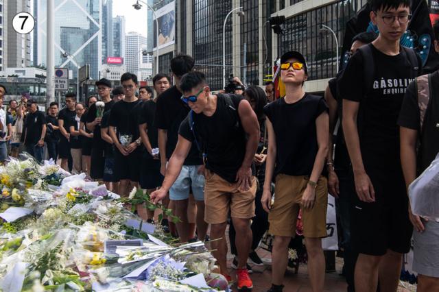A queue of people dressed in black lay flowers at this site on a busy Hong Kong street