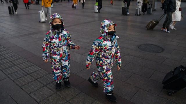 Gêmeos usam máscaras em mercado de rua em Pequim