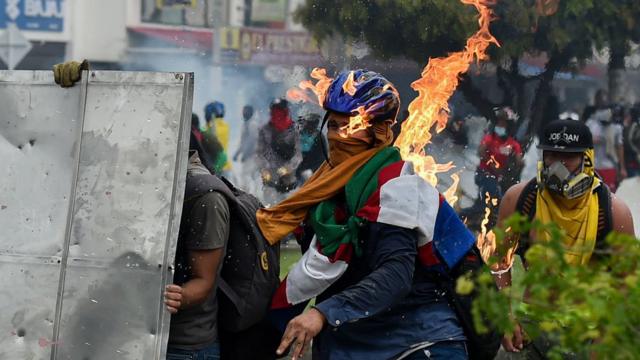 Um manifestante é atingido por um coquetel molotov durante protestos em Cali, Colômbia, no dia 3 de maio.