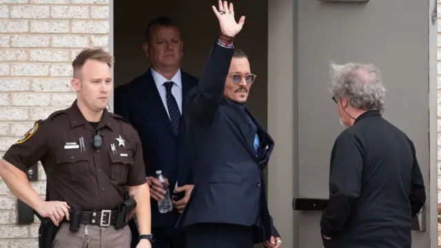 Johnny Depp acena na porta de tribunal