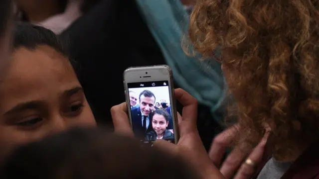 A Tunisian child takes a selfie with French President Emmanuel Macron during a ceremony in memory of the victims of a deadly Islamic State group attack in 2015 at Tunis" Bardo Museum on February 1, 2018.