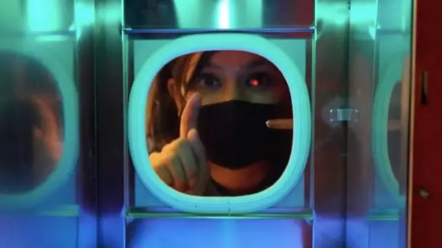 A woman conducting a business meeting through a glass partition