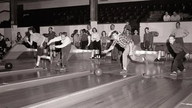 一張黑白照片，照片中是正在打保齡球的年輕男女。