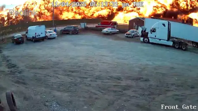 Imagen de cámara de de seguridad que muestra un estacionamiento con la estela en llamas del accidente aéreo en Kentucky