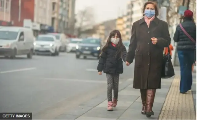 Ọmọbìnrin àti ìyá rẹ̀ tí wọ́n fi nǹkan bo imú wọn