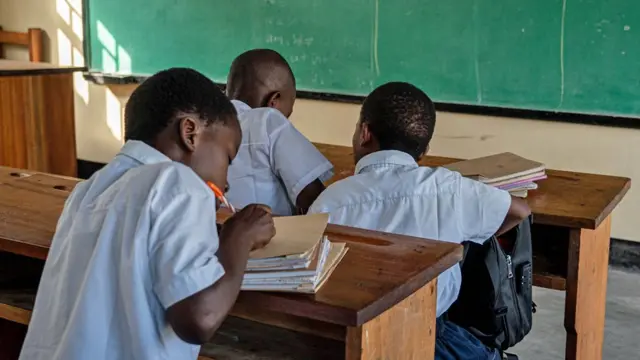 Ɗaluban makarantar firamare ta Rutoboko su na zaune cikin aji sanye da kayan makaranta. Suna zaune a kan kujerar katako yayin da ɗaya daga cikin su ya ke rubuta sunansa a bangon littafi. A gabansu akwai allon da ake koya masu karatu da shi. An ɗauki hoton ne a ranar Litini 1 ga watan Satumba, a birnin Goma na Jamhuriyar Dimokuraɗiyyar Congo.