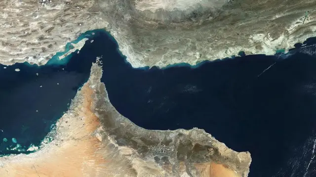 نمای ماهواره‌ای از تنگه هرمز، یک گلوگاه حیاتی برای تأمین انرژی جهان که خلیج فارس را به خلیج عمان متصل می‌کند. این مسیر دریایی مهم، انتقال کالاها از جمله نفت و گاز طبیعی را میان خاورمیانه و سایر نقاط جهان تسهیل می‌کند.