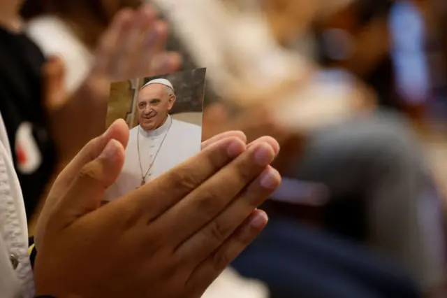 žena drži fotografiju pape Franje