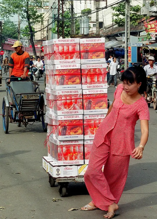 Một chị tiểu thương bán đồ uống tại khu vực Chợ Lớn vào ngày 25/1/2000. Ở phía bên kia đường, các bạn có thể thấy một trụ điện thoại công cộng, một hình ảnh rất quen thuộc tại Sài Gòn vào cuối thập niên 1990 và đầu thập niên 2000.