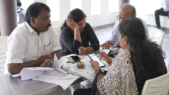 केरल में एसआईआर की प्रक्रिया के दौरान फ़ोन की लाइट में एक बीएलओ से बात करते वोटर्स