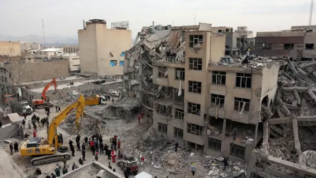 İranlı kurtarma ekipleri, 12 Mart 2026 tarihinde Tahran'ın merkezindeki hasar görmüş konut binalarının enkazı arasında çalışıyor.