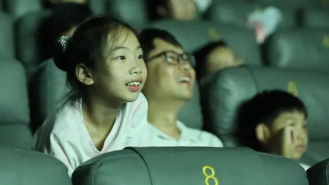 浙江嘉興某電影院內一位小女孩從座位俯前凝視大屏幕(17/8/2025)