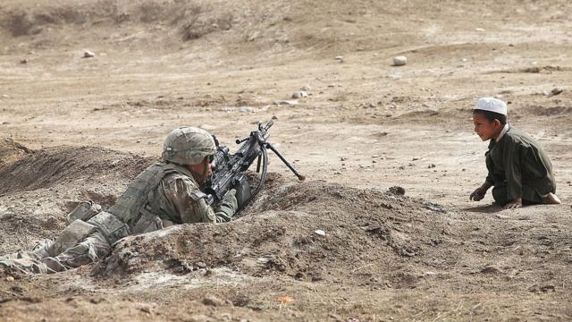 criança observa soldado americano no Afeganistão em 2014