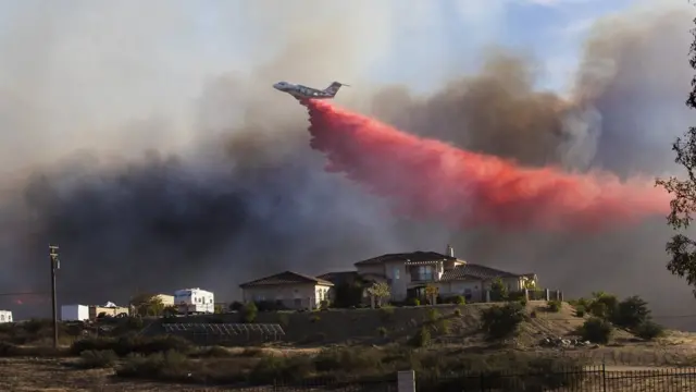 Un avión lanza un retardador de fuego cerca de una casa en Murrieta, California el 7 de diciembre de 2017